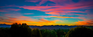 Alt text: Vibrant sunset in Asheville, NC, with bright hues of pink, yellow, and orange criss-crossing across a clear blue sky.