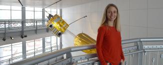 Meg Tilton standing in front of a model of the GOES-8 satellite