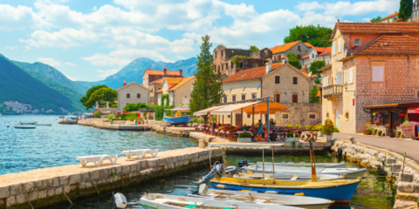 Several boats docked with mountains in the background in the city of Perast in Montenegro.