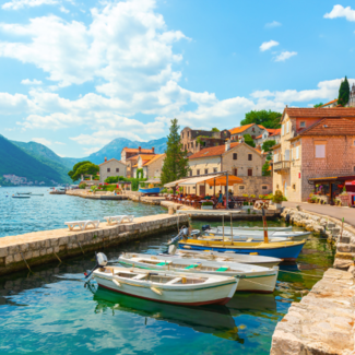 Several boats docked with mountains in the background in the city of Perast in Montenegro.